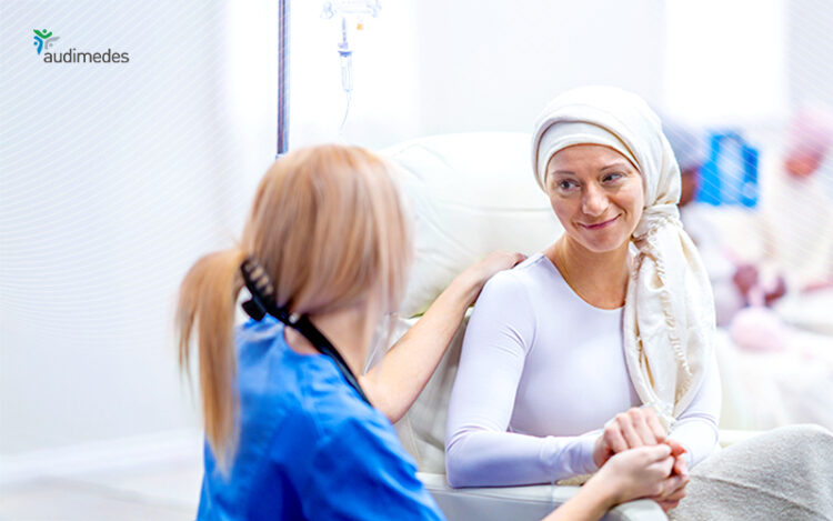 Pflegefachkraft hält die Hand einer Patientin während einer Zytostatika-Infusion und spricht beruhigend mit ihr